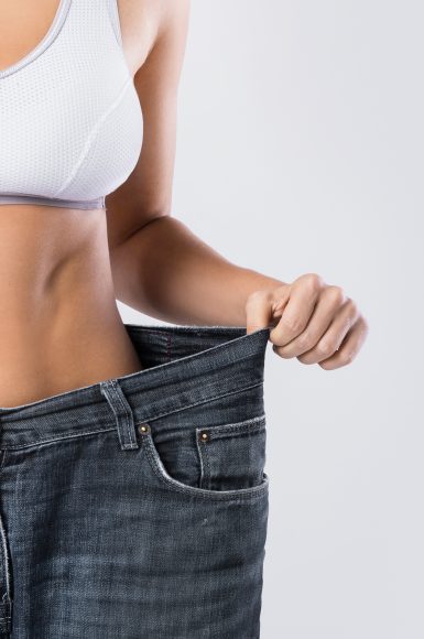 Woman showing result after weight loss wearing on old jeans